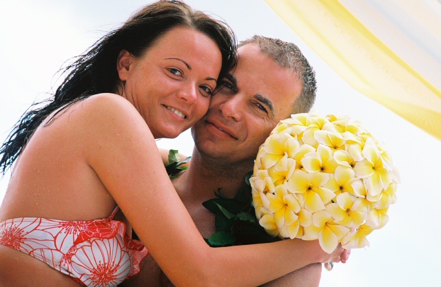 bride in bathing suite hold bouquet of yellow plumerias